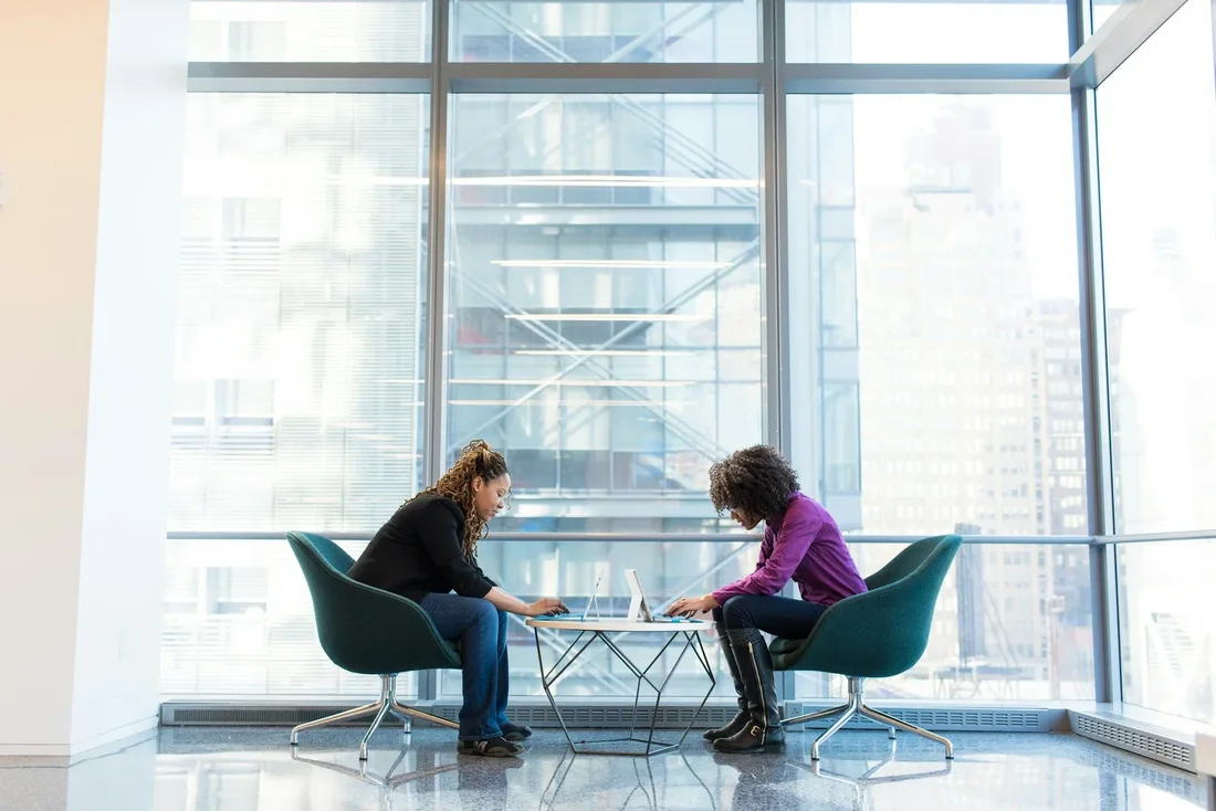 Two professionals working together at a table by a city window